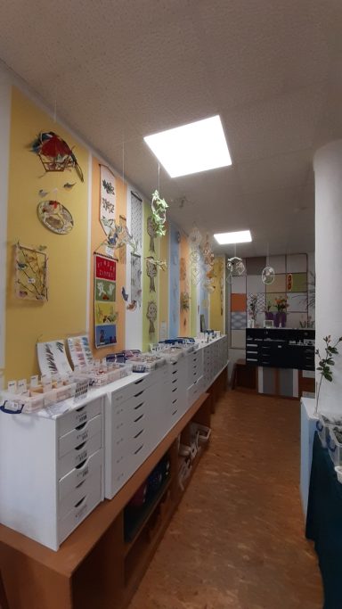 Ein heller Raum mit weißen Schränken und bunten Wanddekorationen.